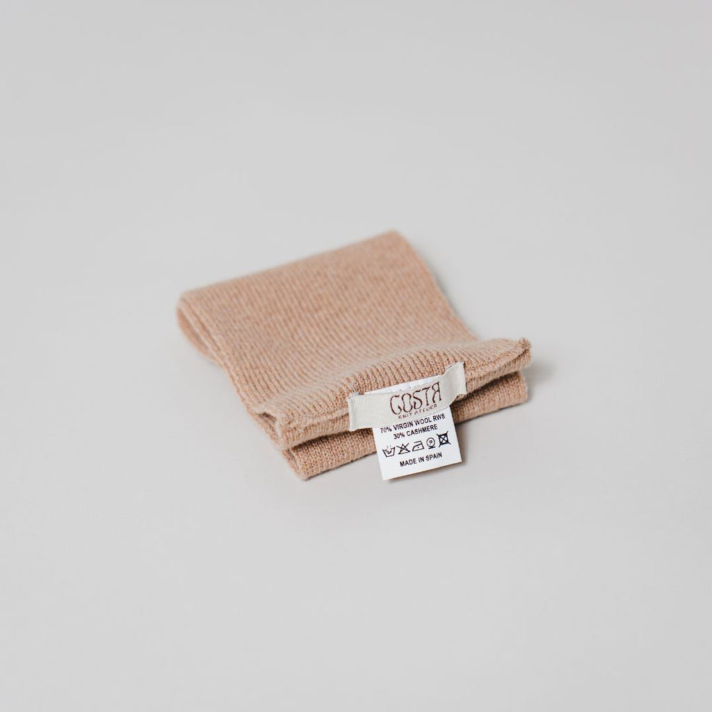 Close-up of the natural fibers and Costa Knit Atelier label on the beige headband, highlighting the soft texture of luxury cashmere.