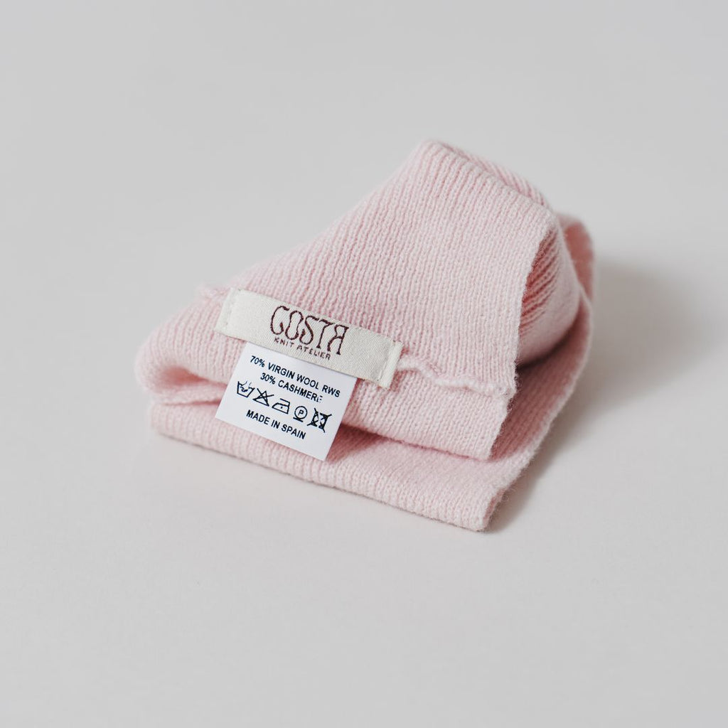 Close-up of the natural fibers and Costa Knit Atelier label on the pink headband, highlighting the soft texture of luxury cashmere.
