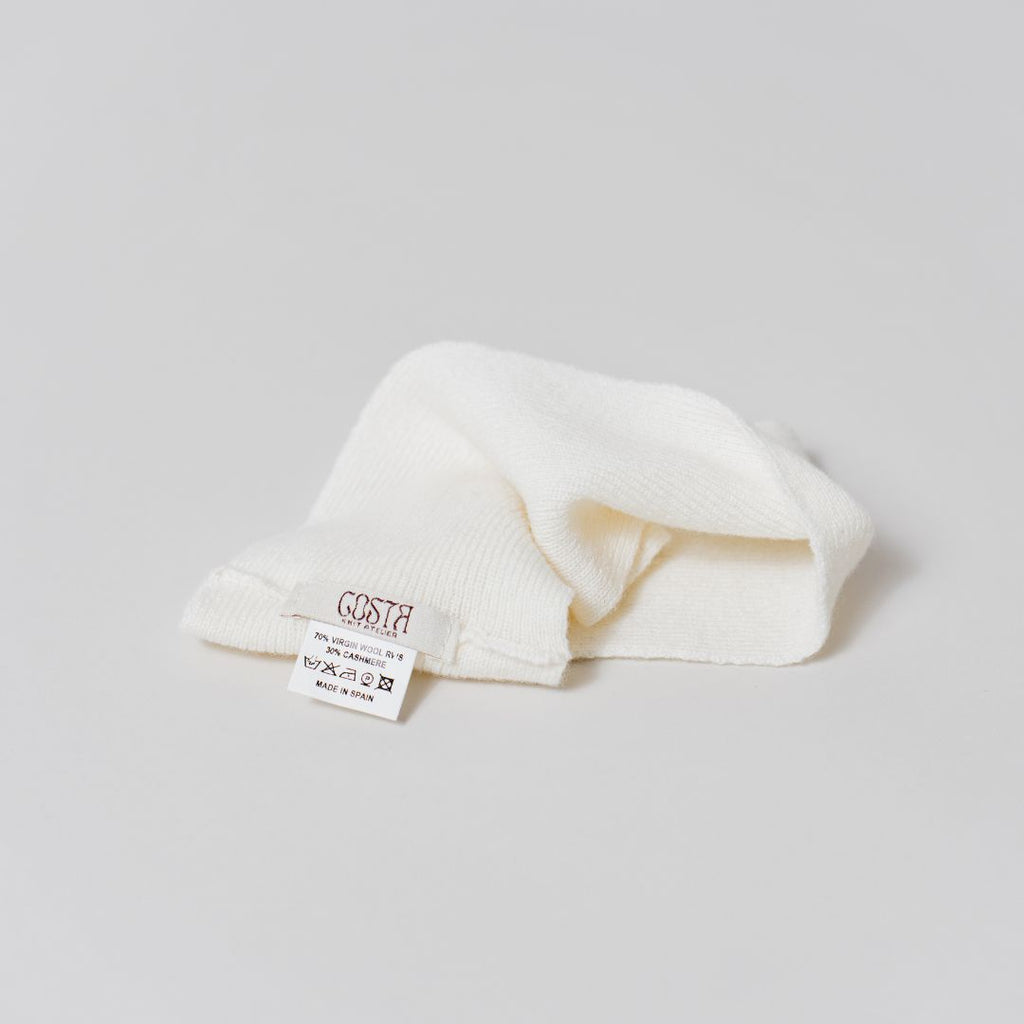 Close-up of the natural fibers and Costa Knit Atelier label on the white headband, highlighting the soft texture of luxury cashmere.