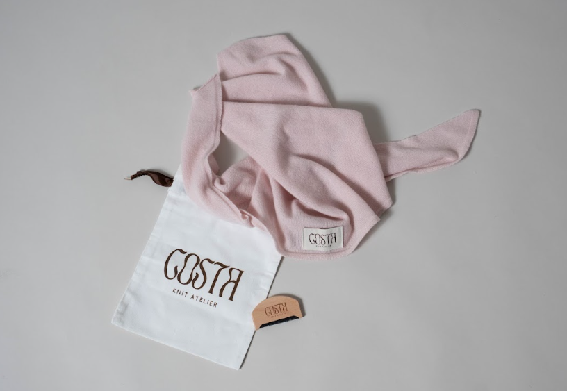 Costa Knit Atelier's Care Ritual set featuring a signature dust bag and wooden brush, designed to maintain knitwear quality and ensure long-term clothing heritage.