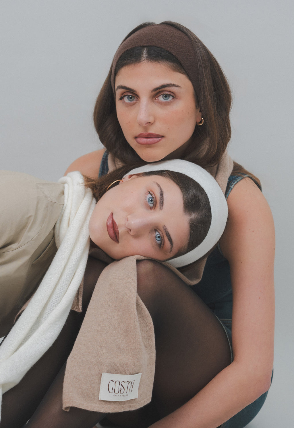 Two models wearing Costa Knit Atelier headbands with their faces together, showcasing the soft texture of premium cashmere and the brand's contemporary artisanal heritage