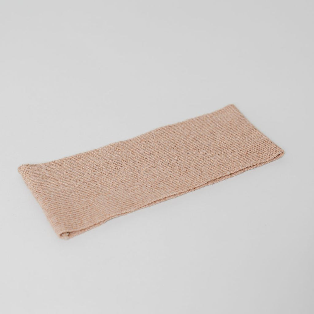 Flat lay of the beige Headband by Costa Knit Atelier, handcrafted from a premium cashmere and extra-fine merino wool blend for ultimate comfort.