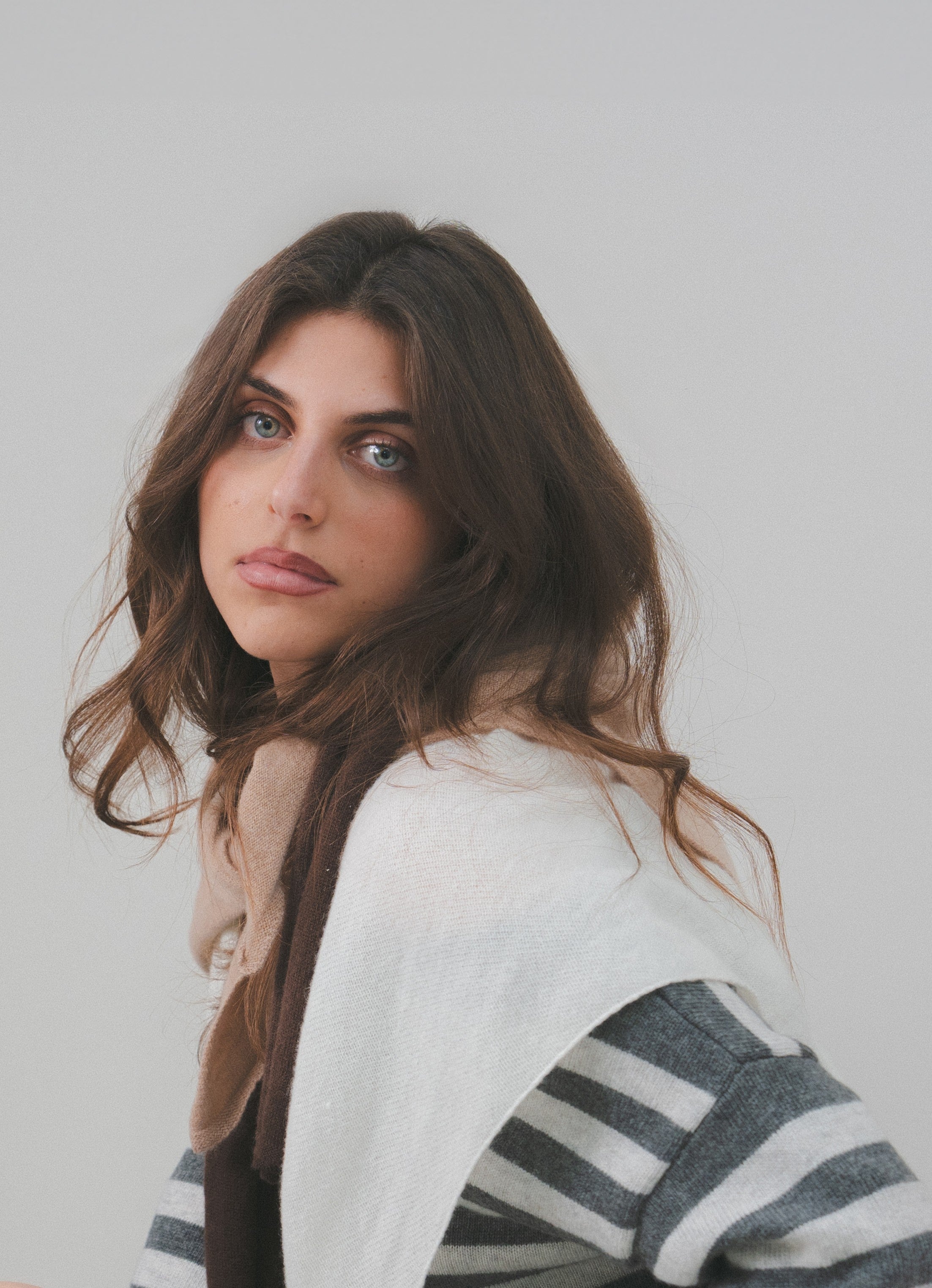 Model showcasing a luxury layering look with Costa Knit Atelier scarves in white, beige, and brown, highlighting the soft texture of premium cashmere and merino wool.