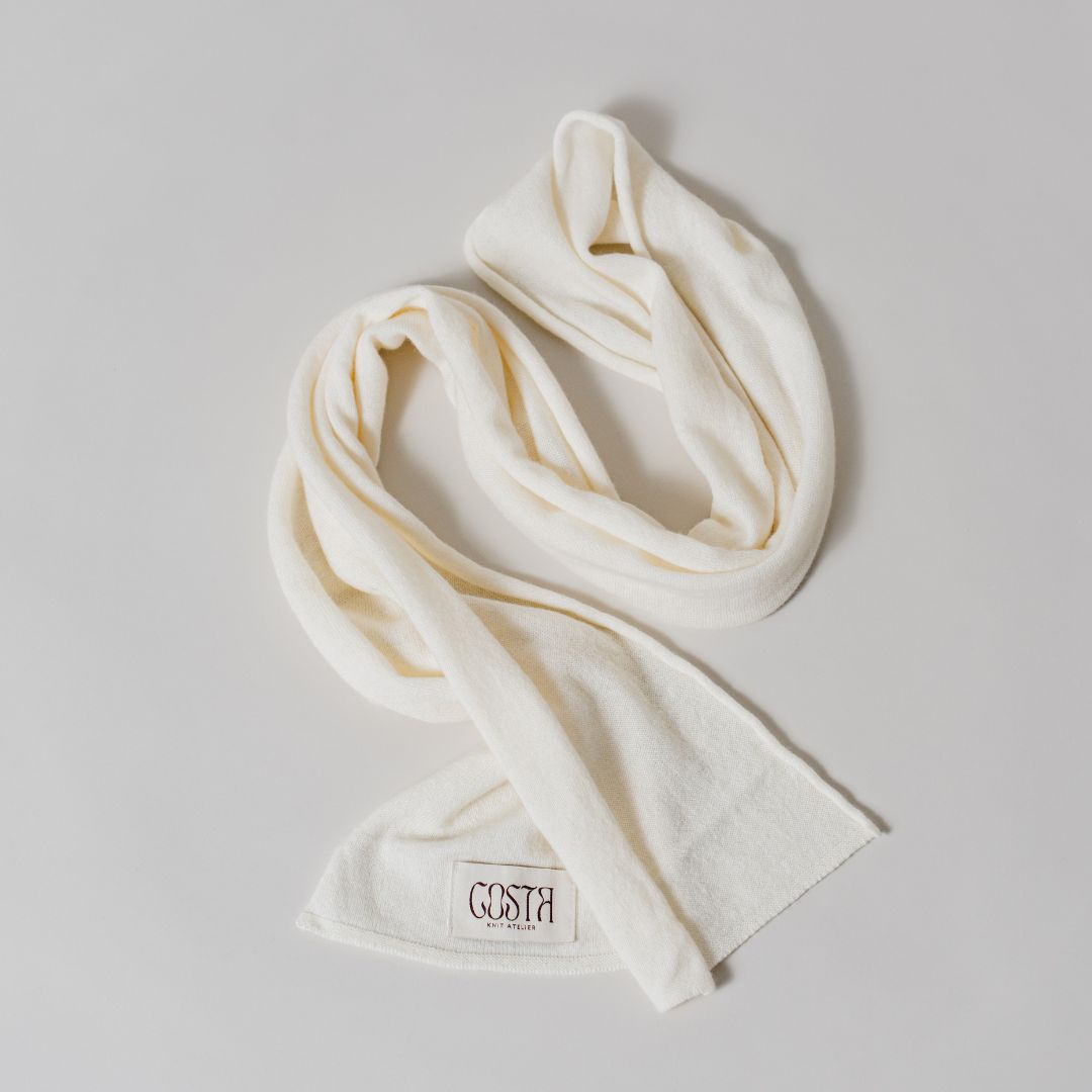 Flat lay of the white Thin Scarf by Costa Knit Atelier, a premium cashmere and merino wool blend with a 90s minimalist silhouette.