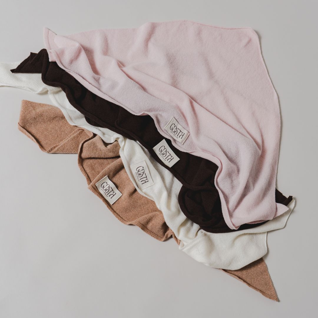 Flat lay of The Triangle Scarf by Costa Knit Atelier in all colours, handcrafted in premium brown cashmere and merino wool blend.