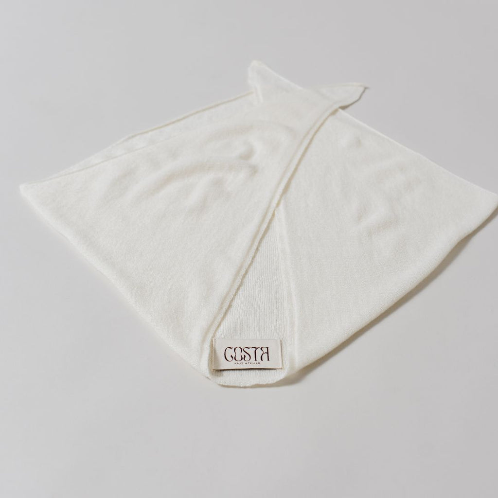 Flat lay of The Triangle Scarf by Costa Knit Atelier, handcrafted in premium white cashmere and merino wool blend